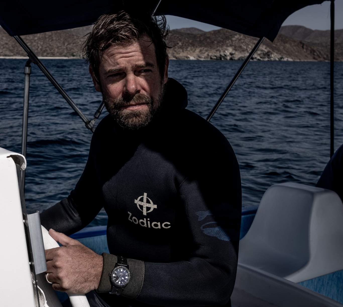 in a boat, wearing a zodiac watch