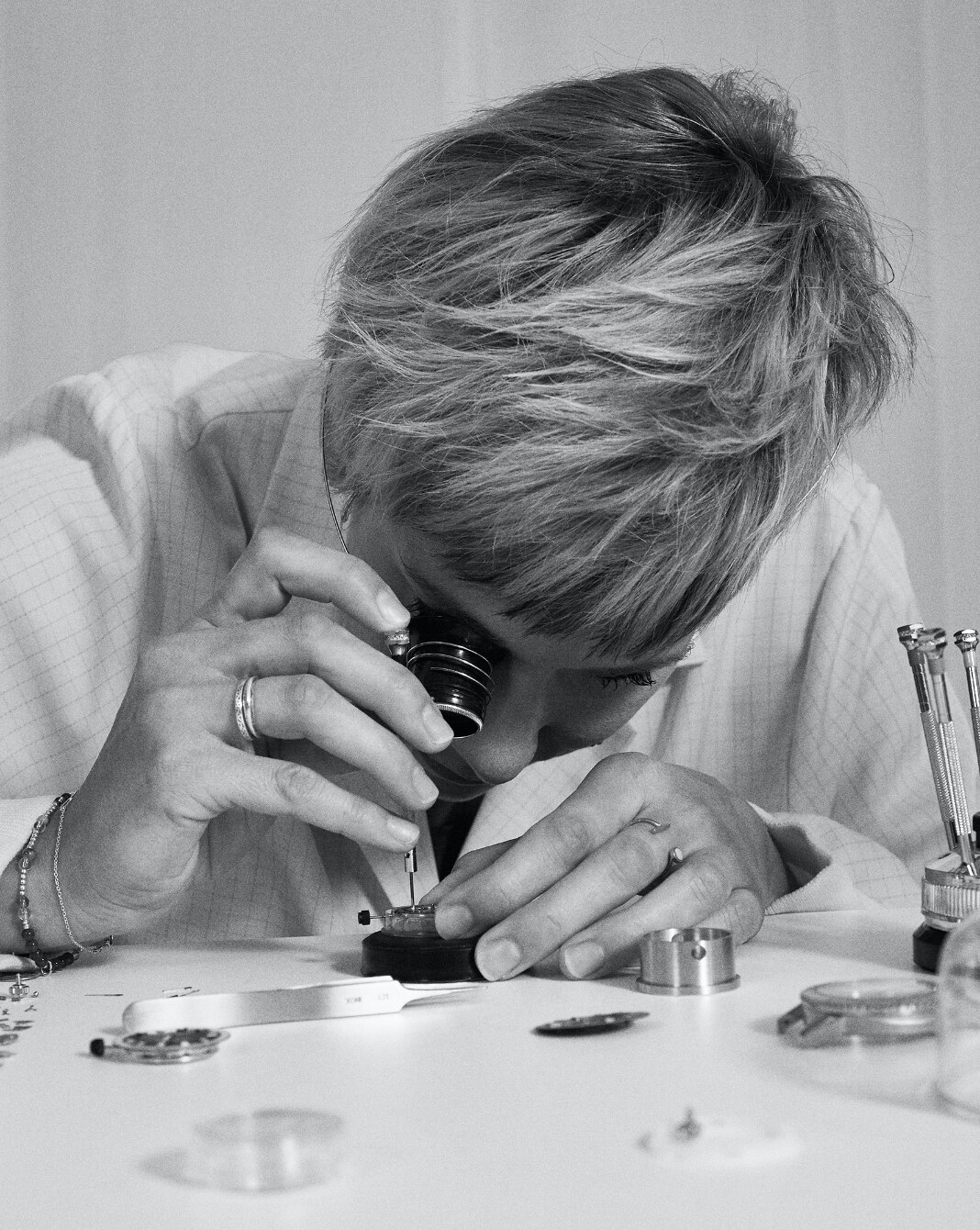 A watchmaker looking through an eyepiece as she works on a watch