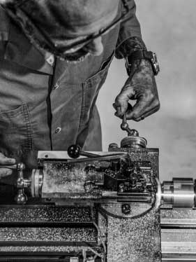 A man uses a lathe to turn and machine the inside of a watch case.