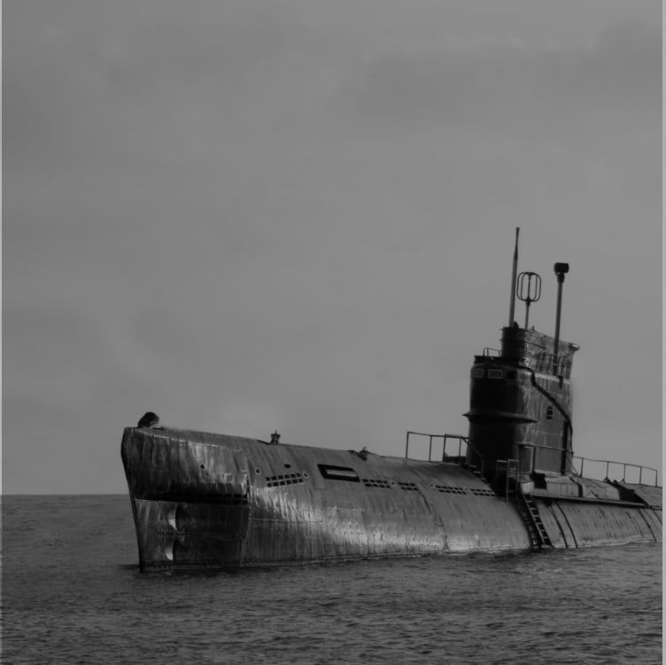 Black and white photo of a submarine at the ocean's surface.