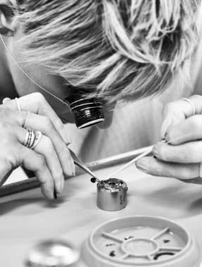 A watchmaker looking through an eyepiece as she works on a watch