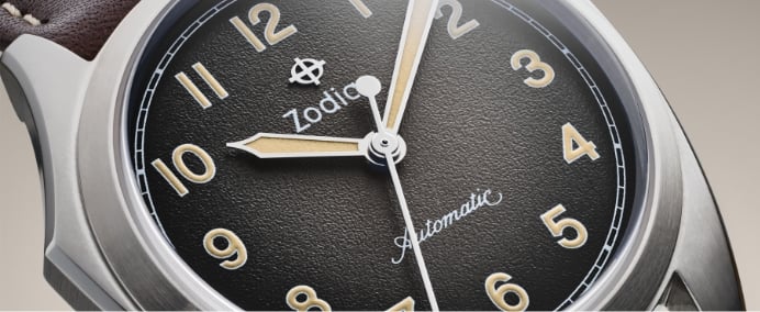 Close-up shot of an Olympos Field watch with a grey textured dial and stainless steel case.